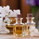 Glass perfume bottles with golden liquid, white flowers, and candlelight symbolizing top, middle, and base fragrance notes.