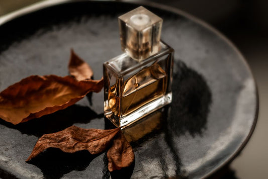 Luxury perfume bottle with amber liquid and dried leaves, symbolizing long-lasting scents like Parfum and Eau de Parfum.