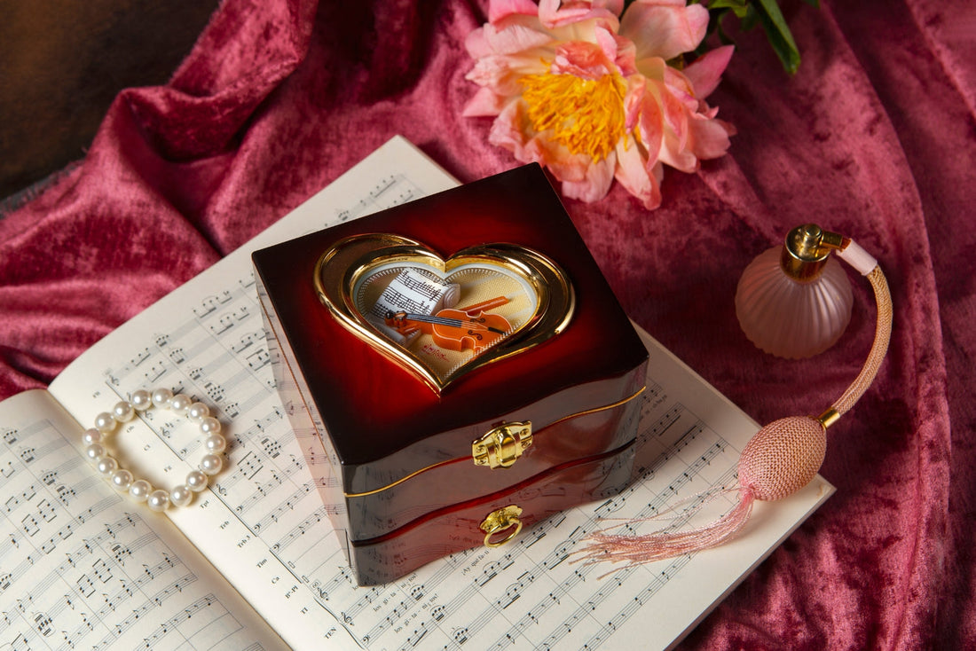 Ornate perfume-themed music box on sheet music with pearls, flower, and pink atomizer
