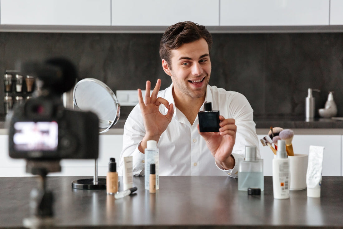 Man filming a fragrance product review while holding a black perfume bottle