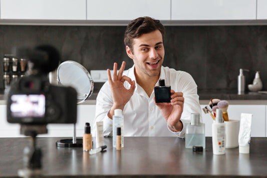Man filming a fragrance product review while holding a black perfume bottle