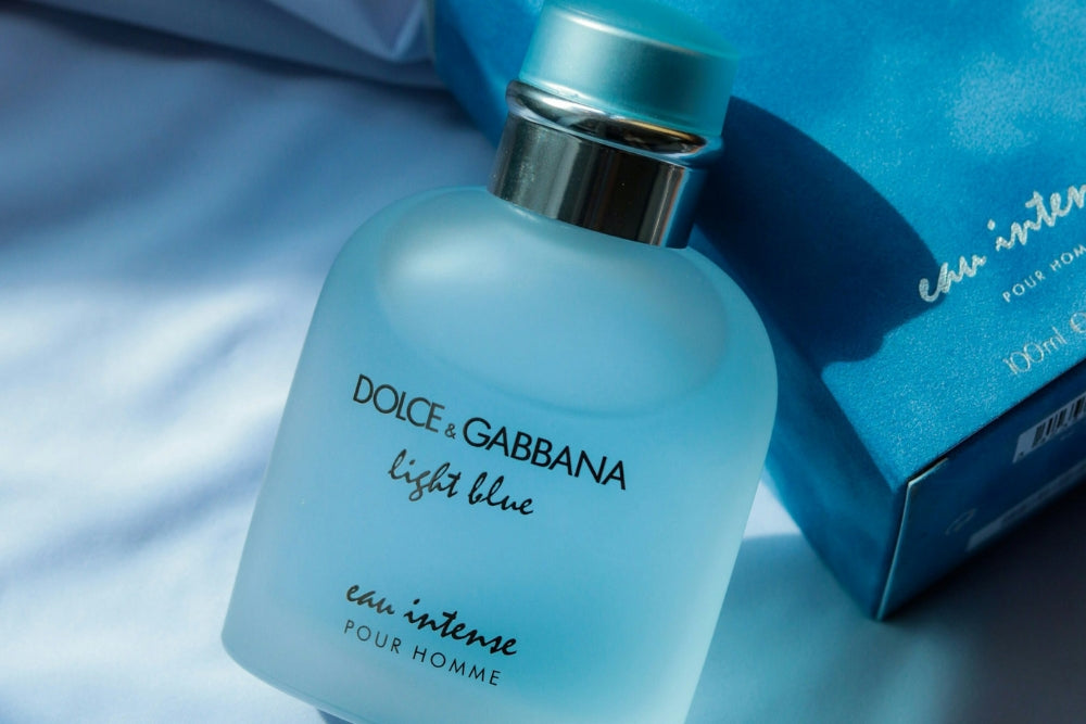 A bottle of Dolce & Gabbana Light Blue Eau Intense Pour Homme cologne, with its box visible in the background.