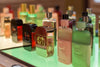Gucci perfume bottles, including Gucci Guilty and Gucci Bloom, arranged on a green-lit shelf in a store.