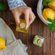 small glass bottle filled with bergamot, surrounded by fresh lemons and limes emitting fresh scent