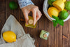 small glass bottle filled with bergamot, surrounded by fresh lemons and limes emitting fresh scent