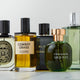 A lineup of various men's cologne bottles, including brands like Diptyque, D.S. & Durga, Chanel, Arquiste, and Hermès.